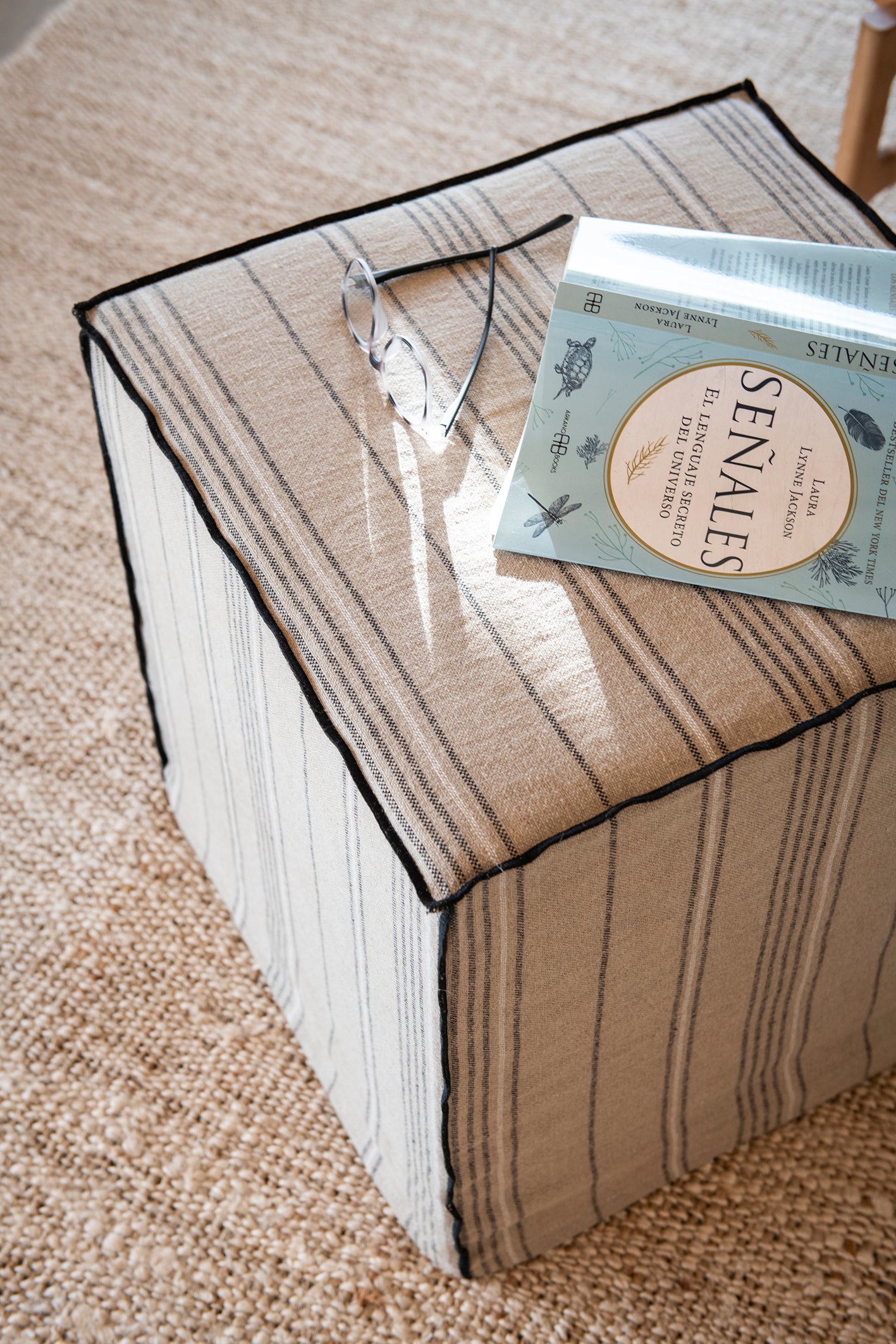 Banqueta de tela en lino con rayitas que sirve como mesa auxiliar o reposa-pies
