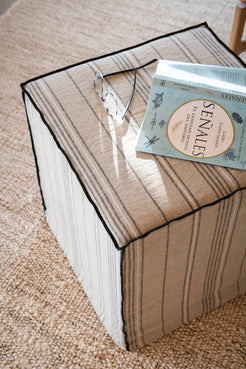 Banqueta de tela en lino con rayitas que sirve como mesa auxiliar o reposa-pies
