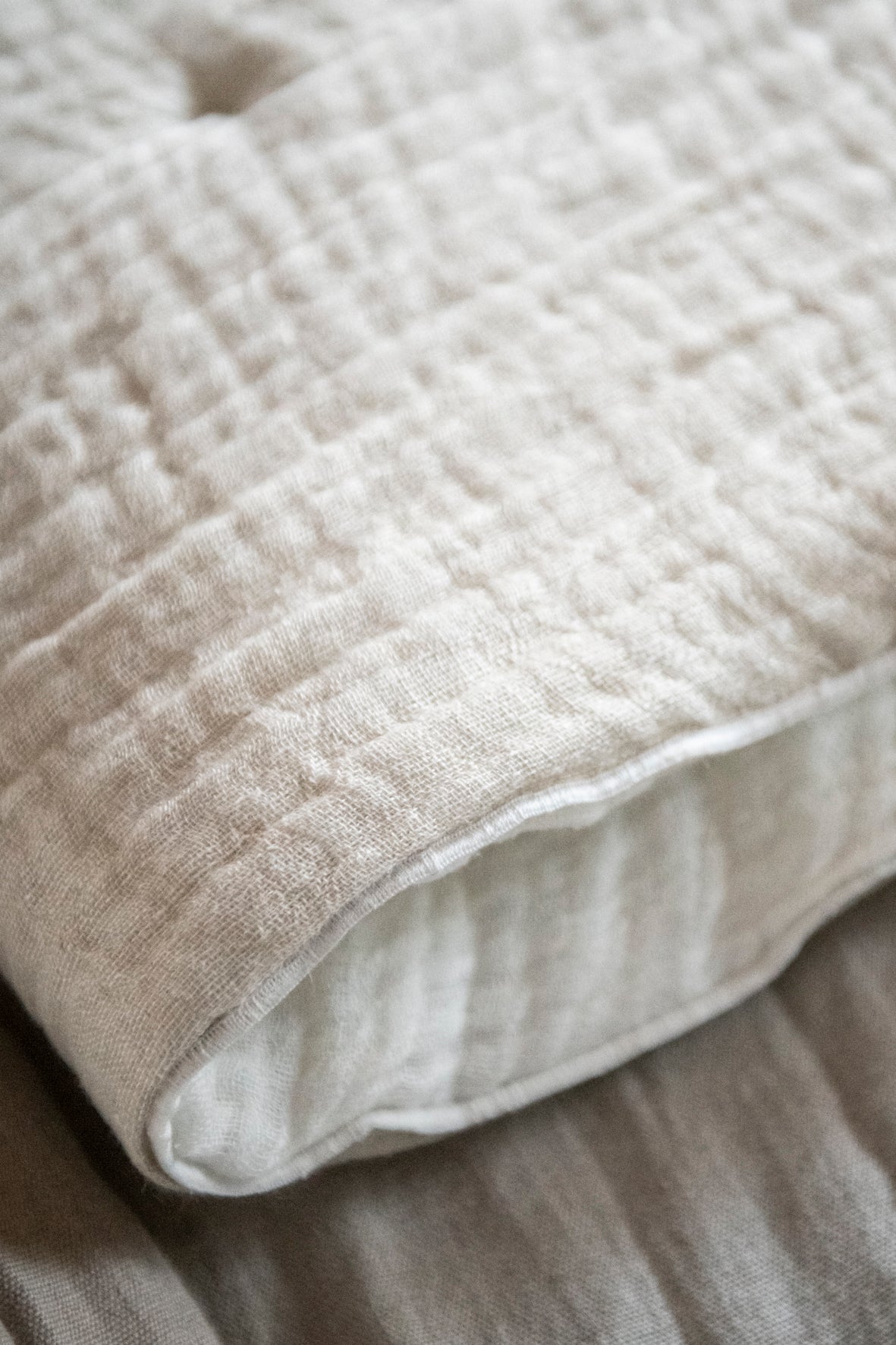Plaid para decorar a los pies de la cama reversible en lino blanco y begie y acolchado